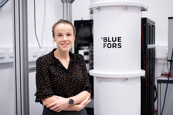 Dr Xanthe Croot pictured next to the BlueFors refrigerator in the Superconducting Quantum Circuits Laboratory.